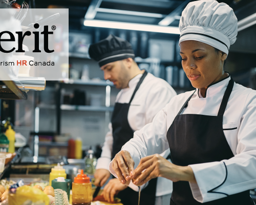 Two chefs skillfully preparing food in a bustling kitchen, with the word "emertit" prominently displayed.