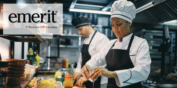 Two chefs skillfully preparing food in a bustling kitchen, with the word "emertit" prominently displayed.